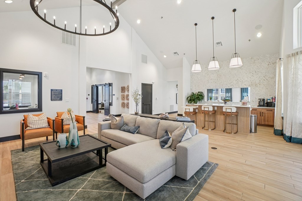 A modern living room with a grey sofa, a coffee table, and a chandelier.