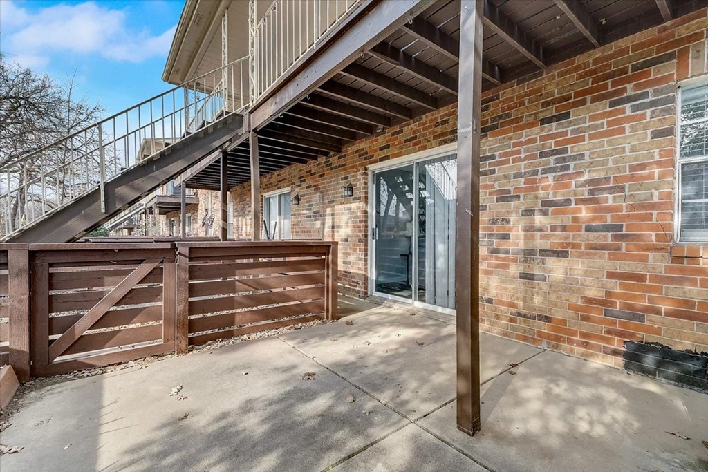the front door of a brick house with a wooden fence and a staircase