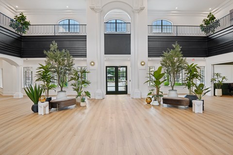 A large room with a wooden floor and a balcony with plants on it.