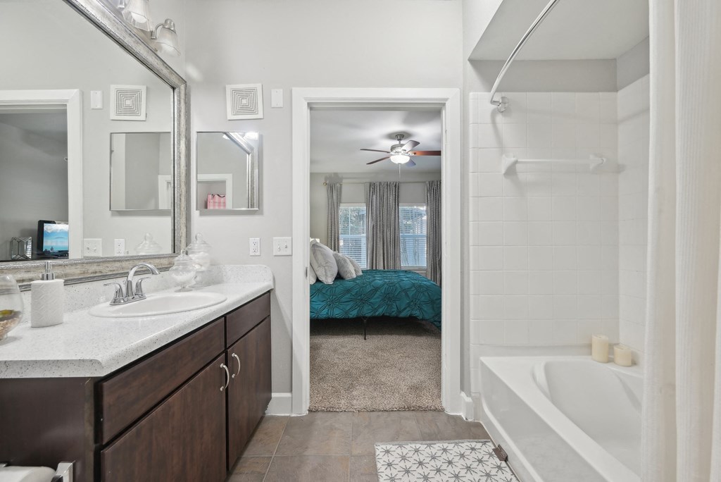 A bathroom with a white tub and a bed in the background.
