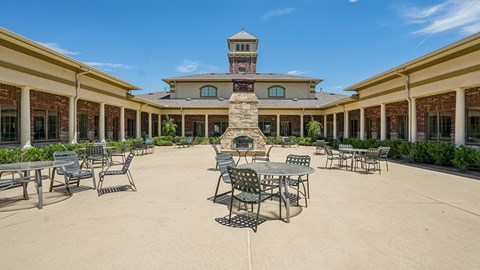 A courtyard with tables and chairs and a building in the background.