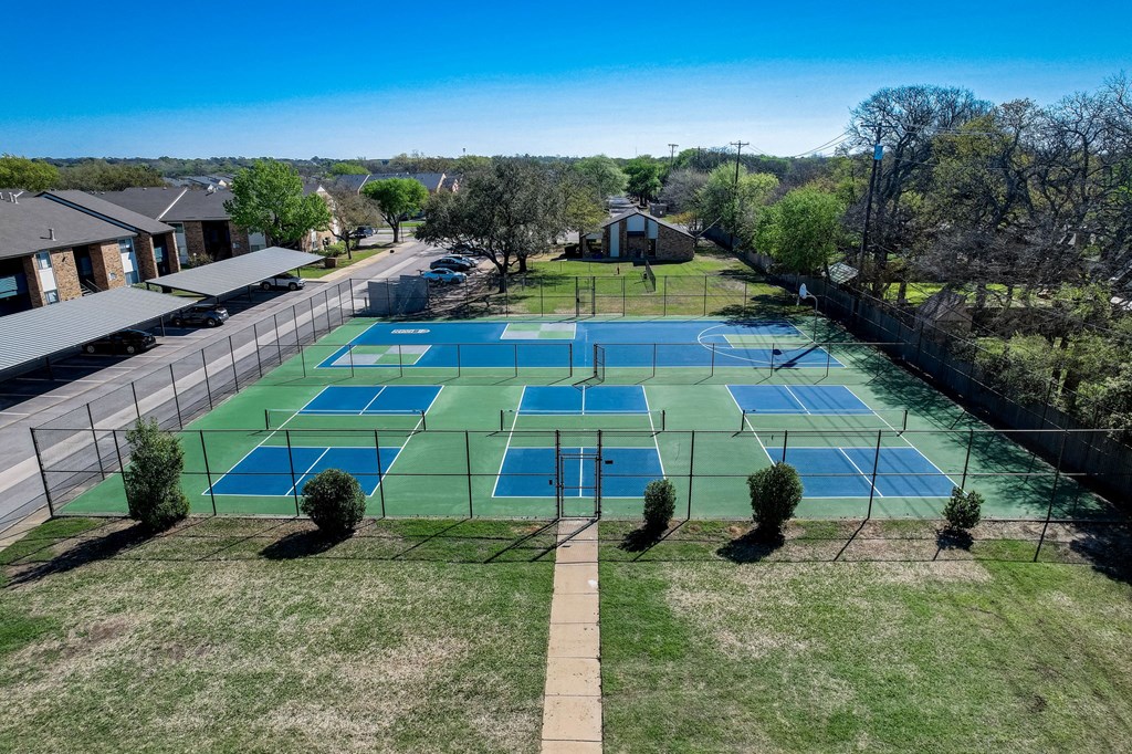 an aerial view of a tennis court with tennis courts on the grass