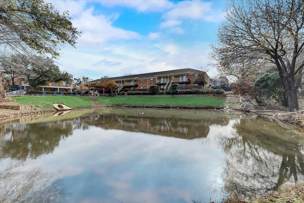 a pond in front of a house with a house in the background