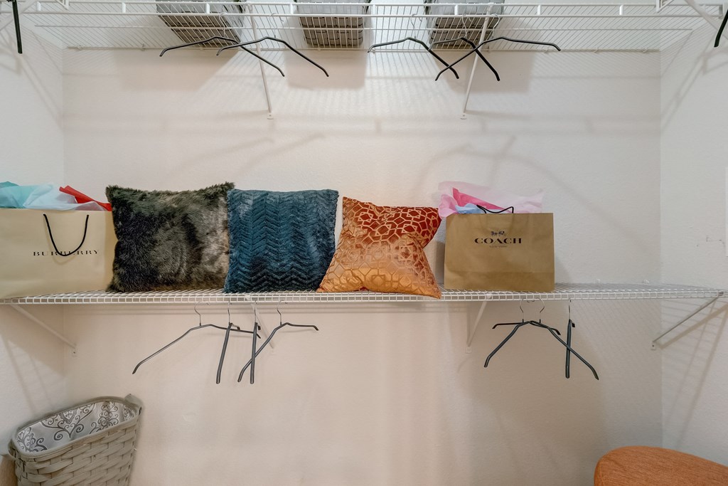 a closet filled with bags and pillows on a shelf