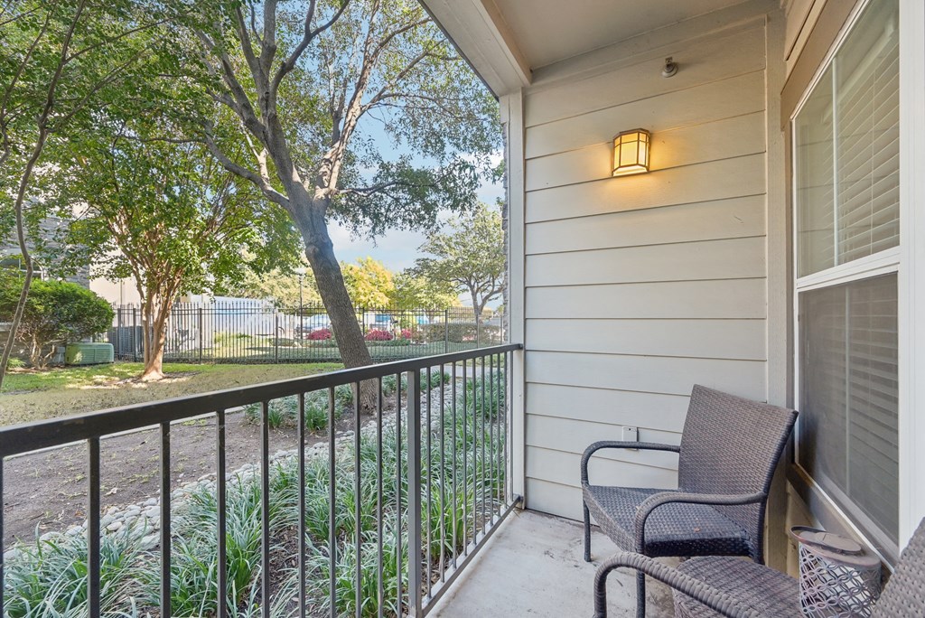 A balcony with a chair and a lamp on the wall.