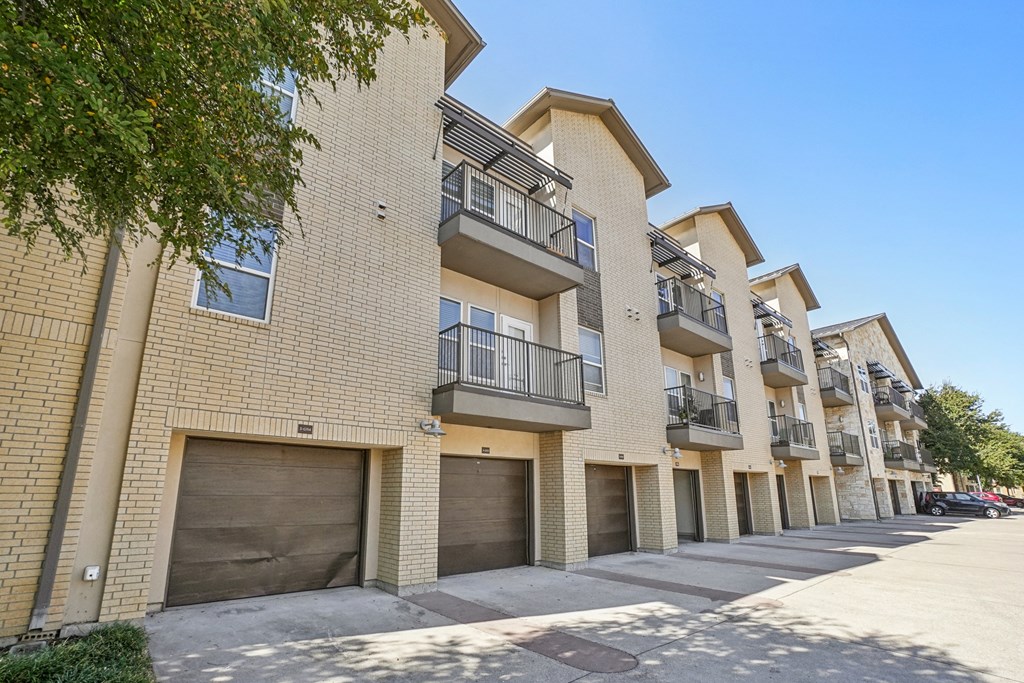 A row of apartment buildings with balconies and garage doors.