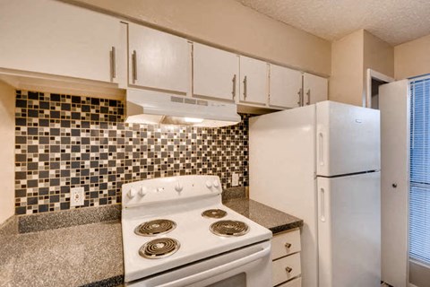 A white stove in a kitchen with a black and white tiled backsplash.