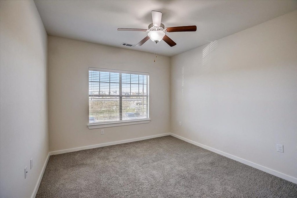 an empty room with a ceiling fan and a window