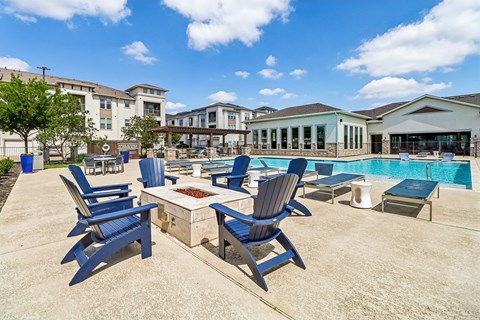 A poolside area with blue chairs and a table.