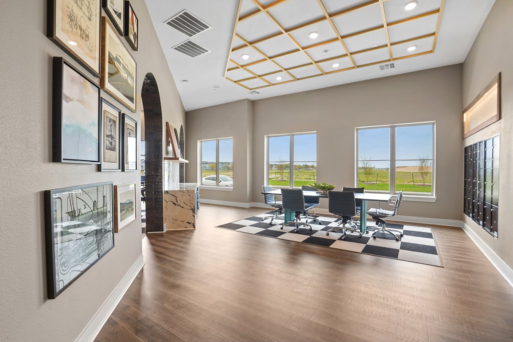 A spacious room with a long table and chairs, a black and white rug, and pictures on the wall.