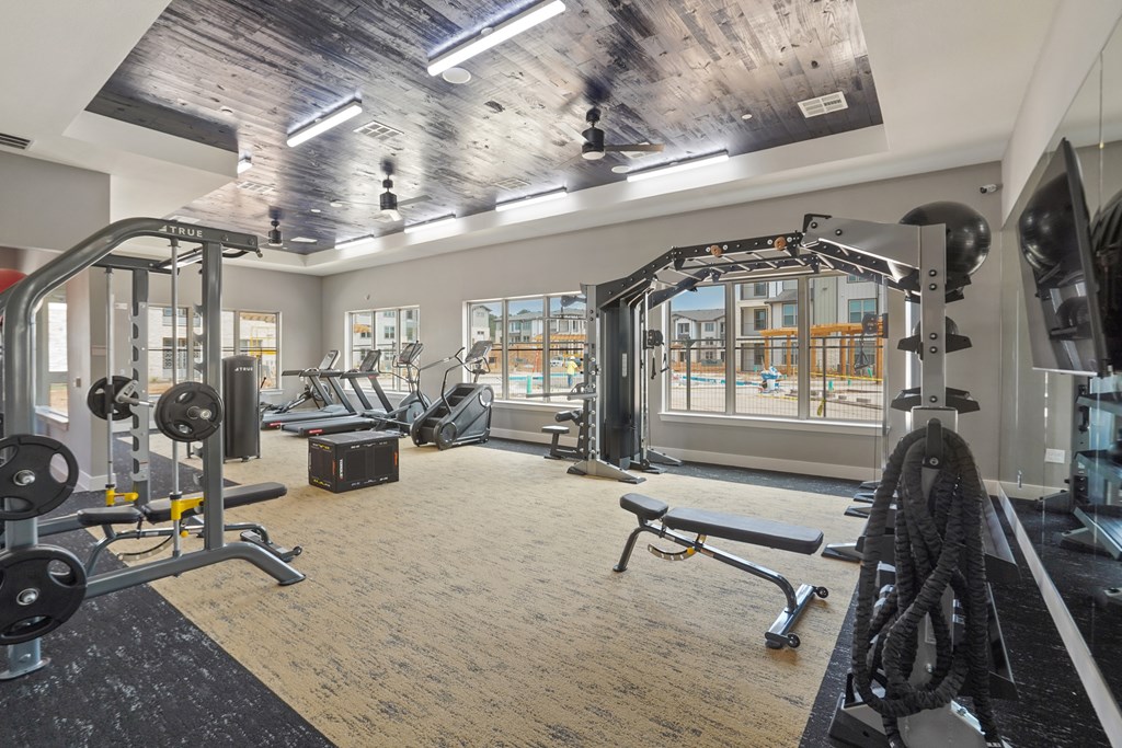 A gym with a variety of equipment including a treadmill, weights, and a bench.