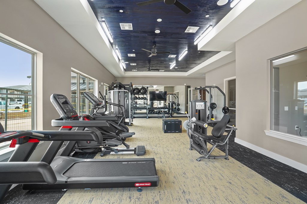 A gym with treadmills, weights, and exercise equipment.