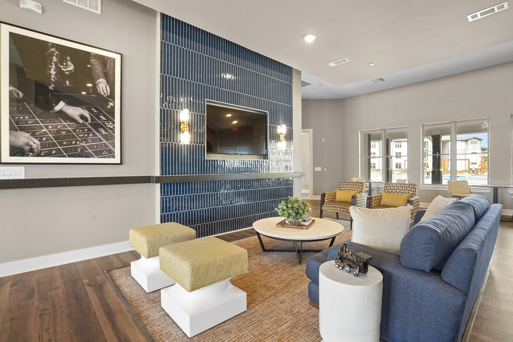 A living room with a blue couch and a television mounted on the wall.