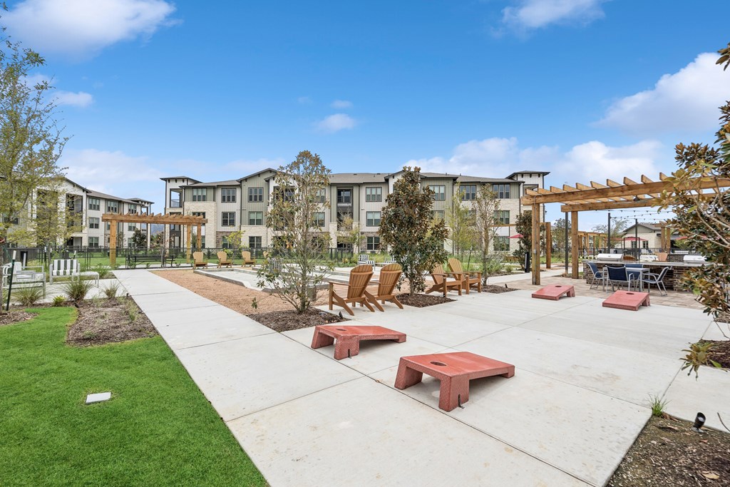 A sunny day at a park with benches and a building in the background.