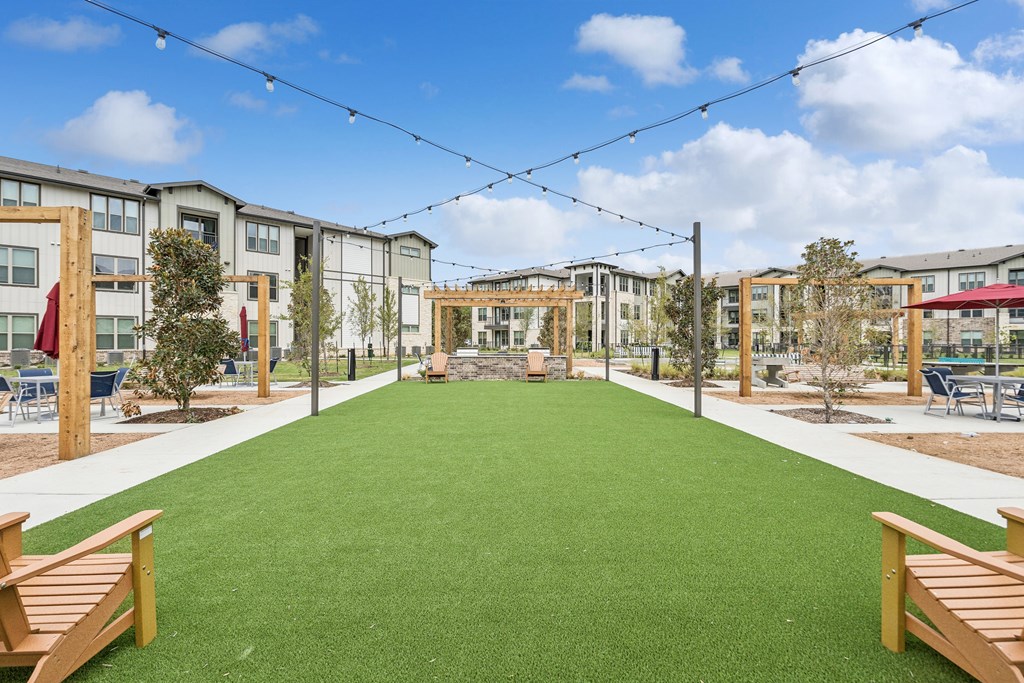 A grassy area in front of apartment buildings with wooden benches.