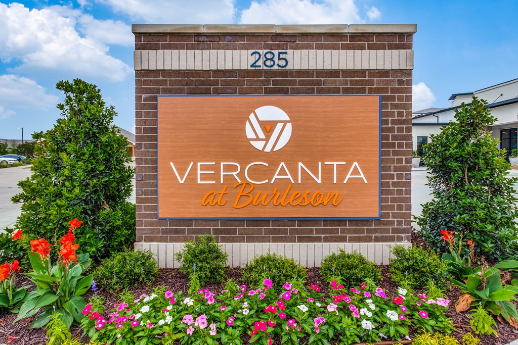A sign for Vercanta at Burleson is surrounded by flowers.