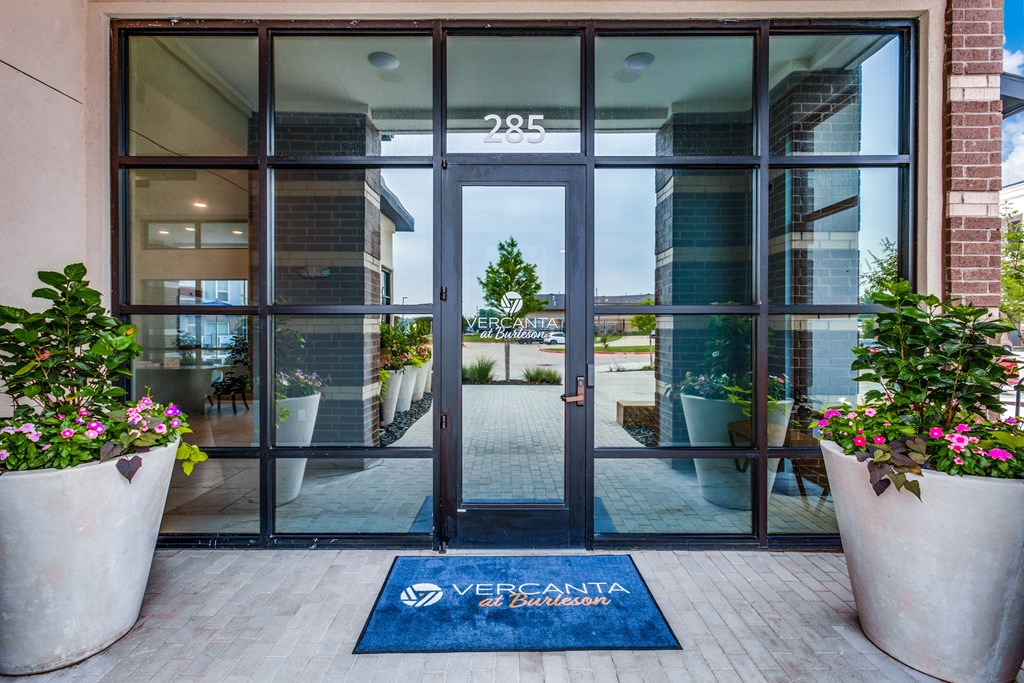 The entrance to a building with a glass door and a mat that says Vercanta on it.