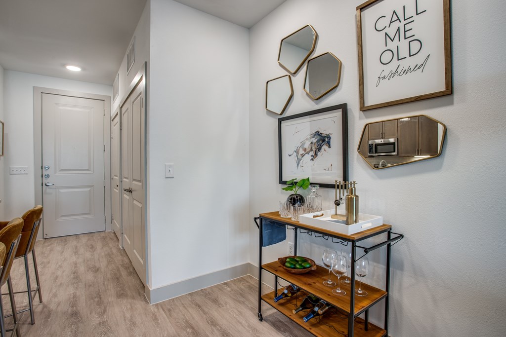 A hallway with a bar cart and a framed picture on the wall.