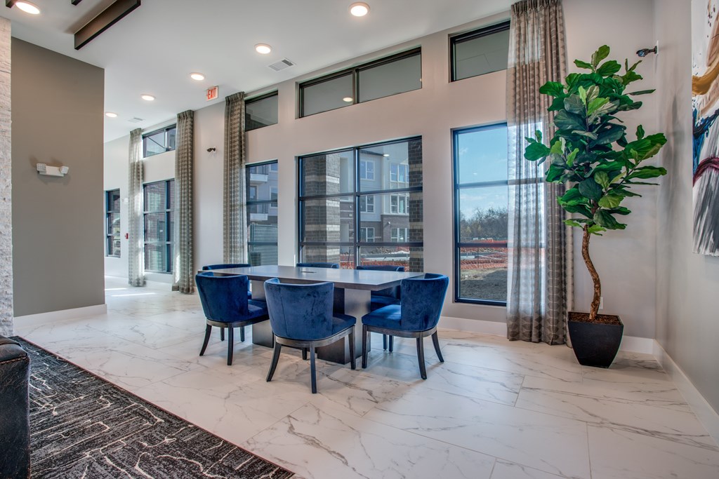 A room with a table and chairs in front of a window.