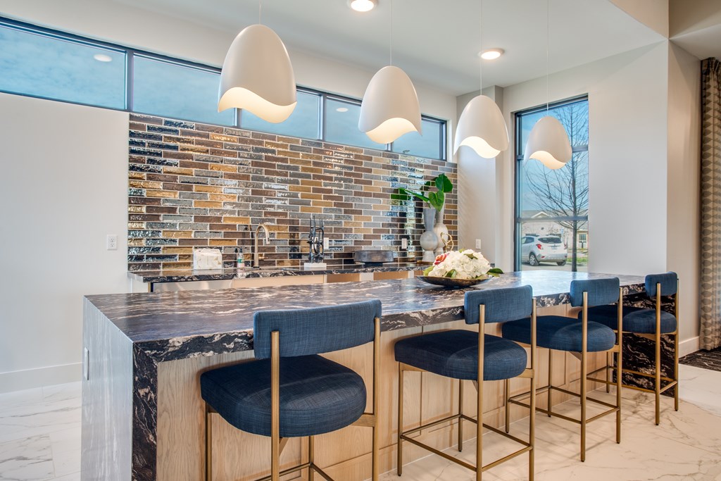 A kitchen with a marble countertop and blue chairs.