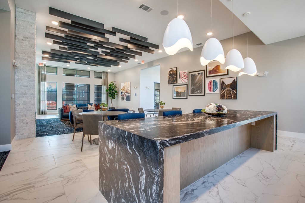 A modern kitchen with a marble island and pendant lights.