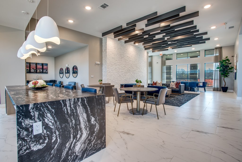 A modern kitchen with a marble island and a dining area with a table and chairs.
