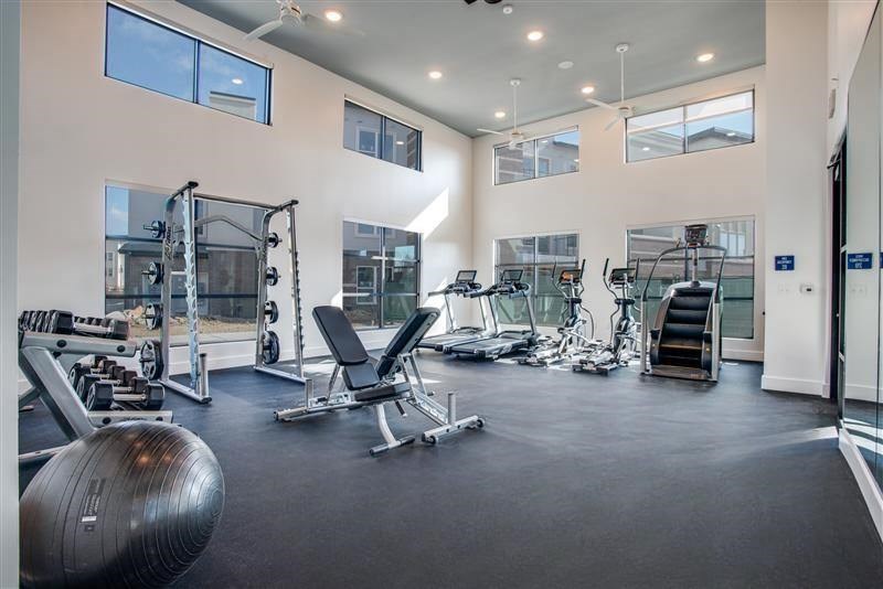 A spacious gym with various exercise equipment and a large mirror on the wall.