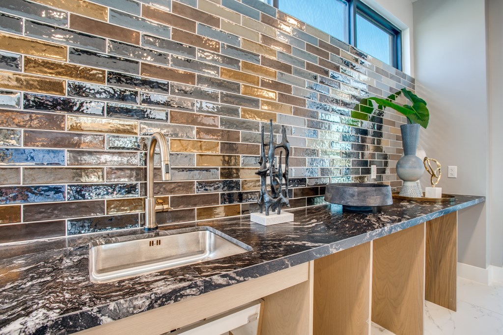 A kitchen with a marble countertop and a tiled backsplash.