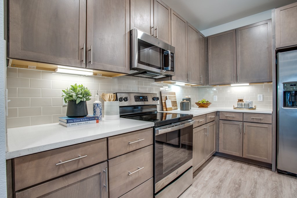 A kitchen with brown cabinets and a stainless steel refrigerator.