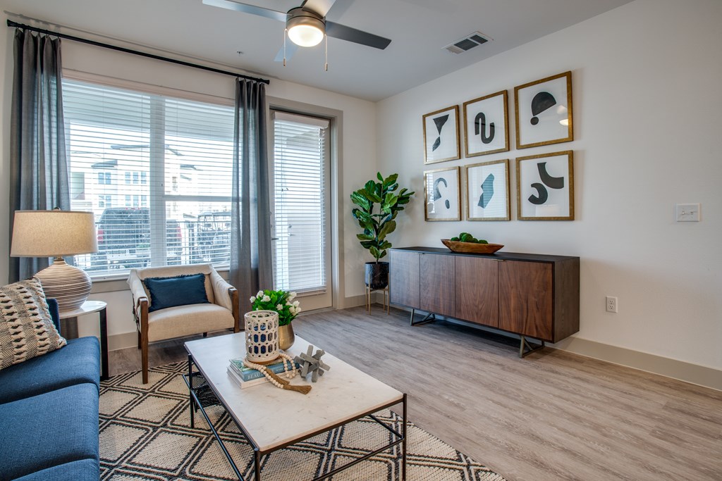 A living room with a blue couch, a coffee table, and a plant.