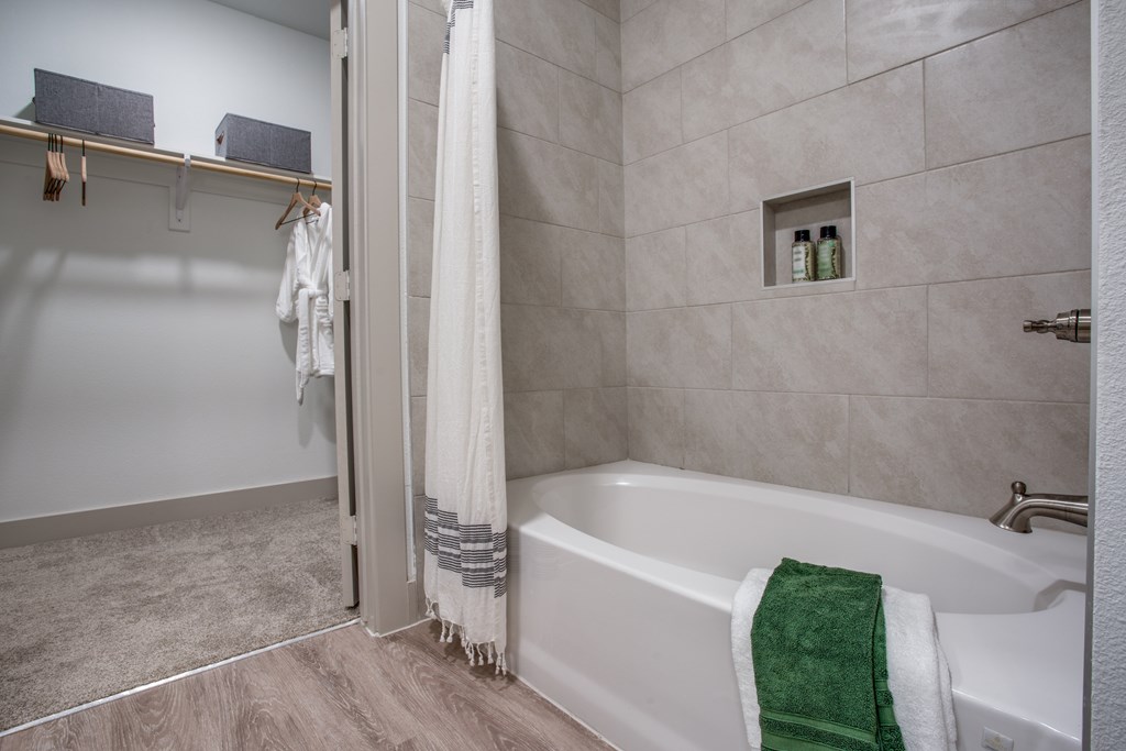 A white bathtub with a green towel on it.