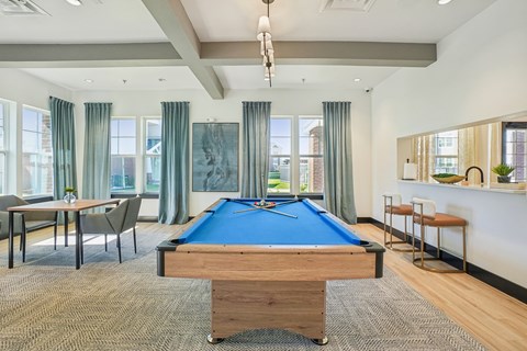 A room with a pool table and a bar area.