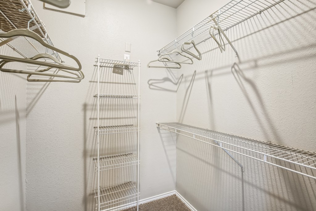 A white closet with metal racks and hangers.