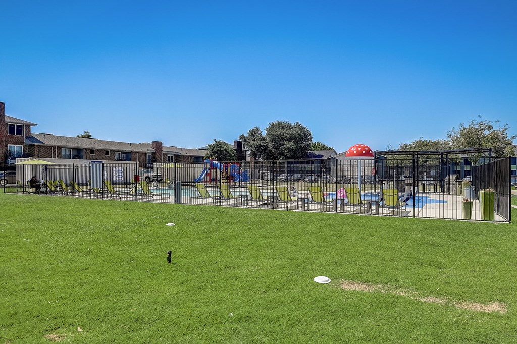 a fenced in grassy area with a playground in the background