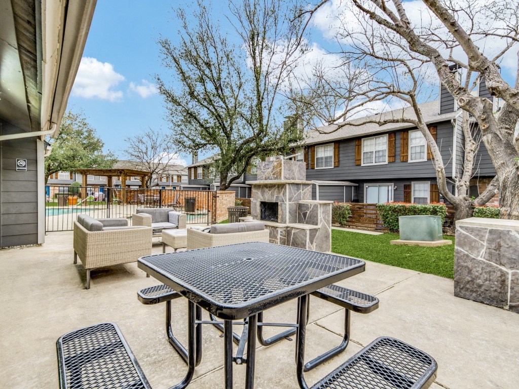 a patio with a table and chairs and a fire pit