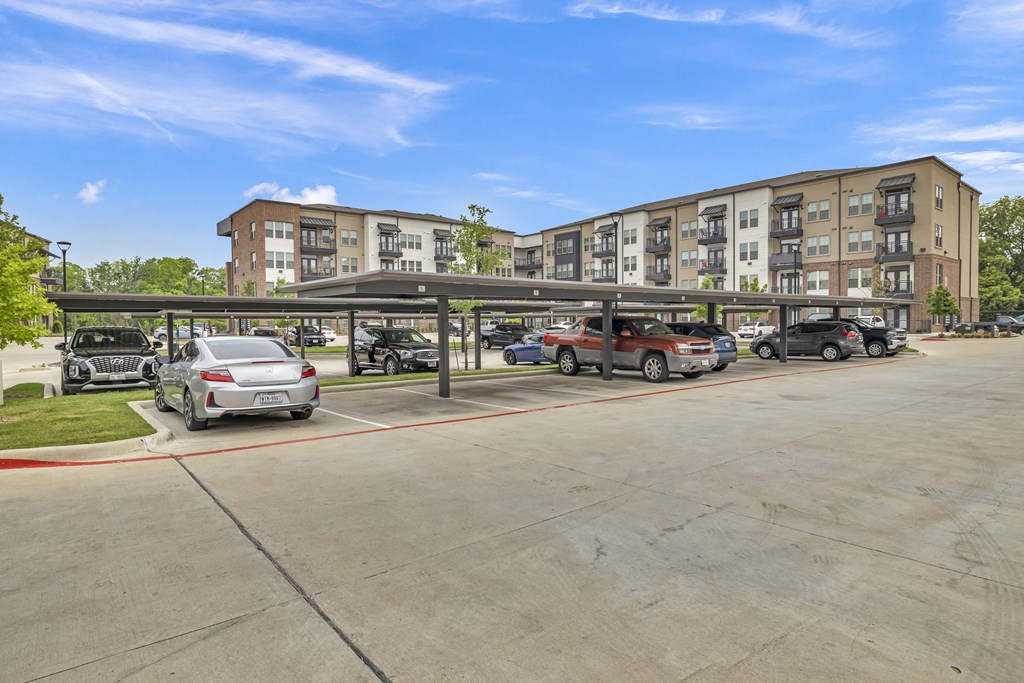 an empty parking lot with cars in front of an apartment building