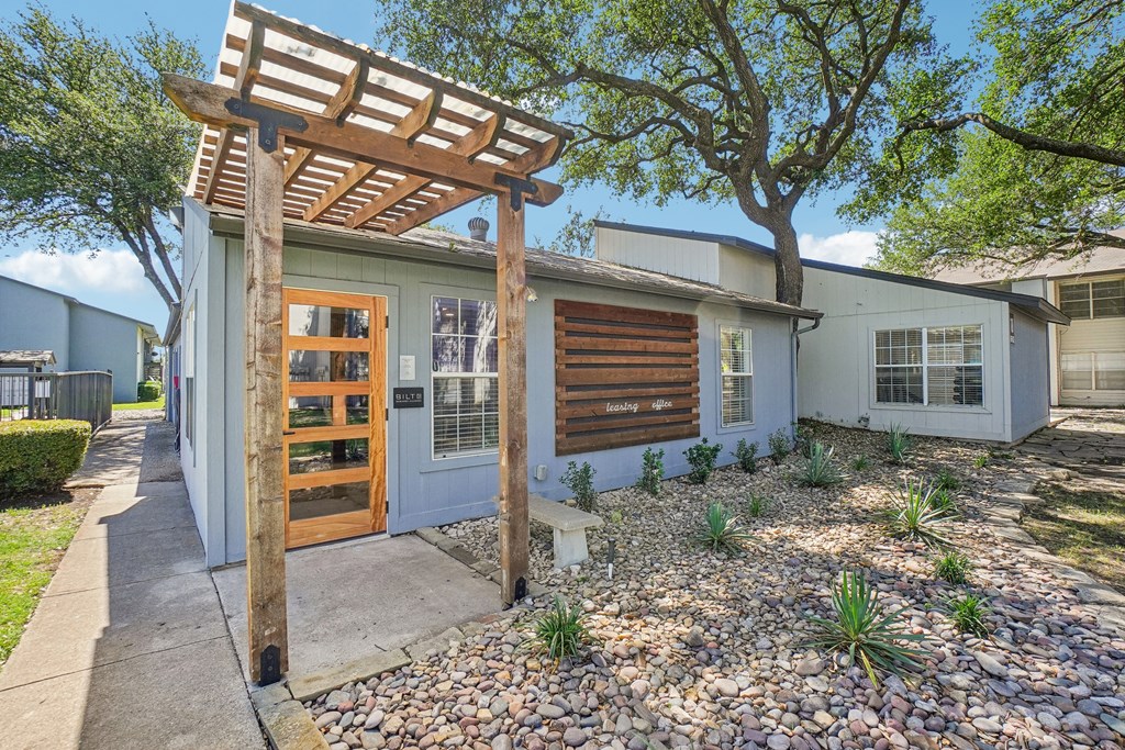 A house with a wooden pergola attached to it.