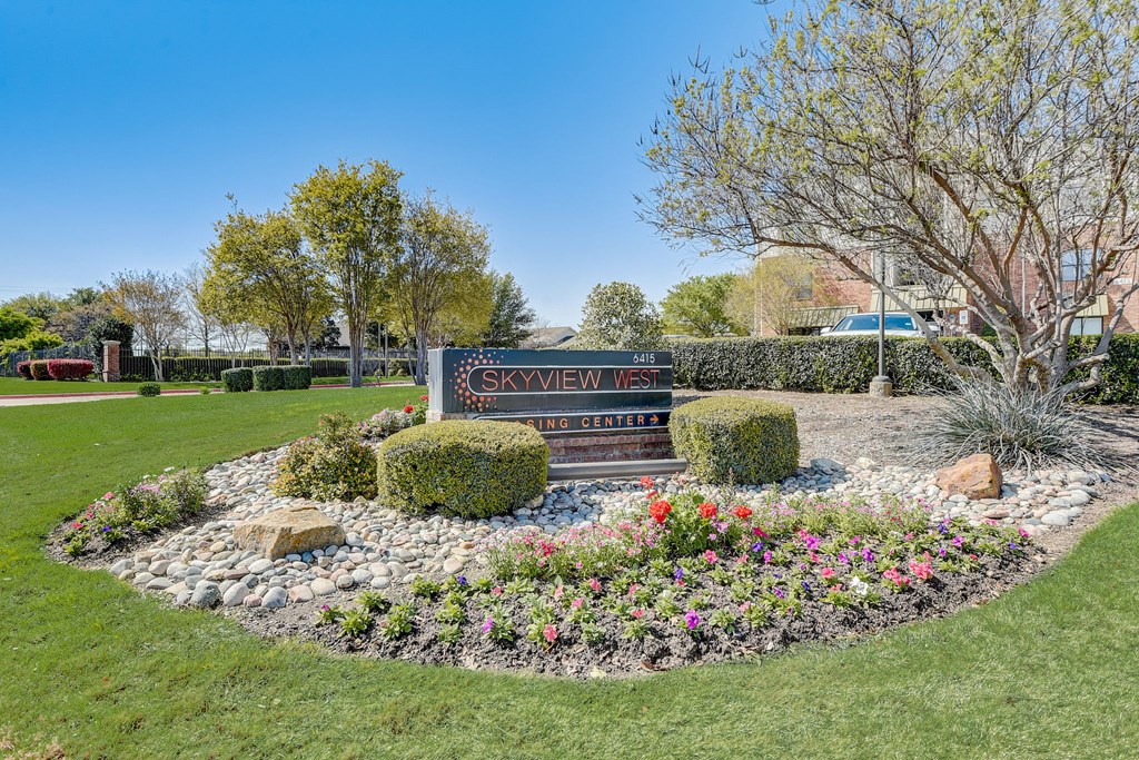 a park with flowers and a sign in the grass