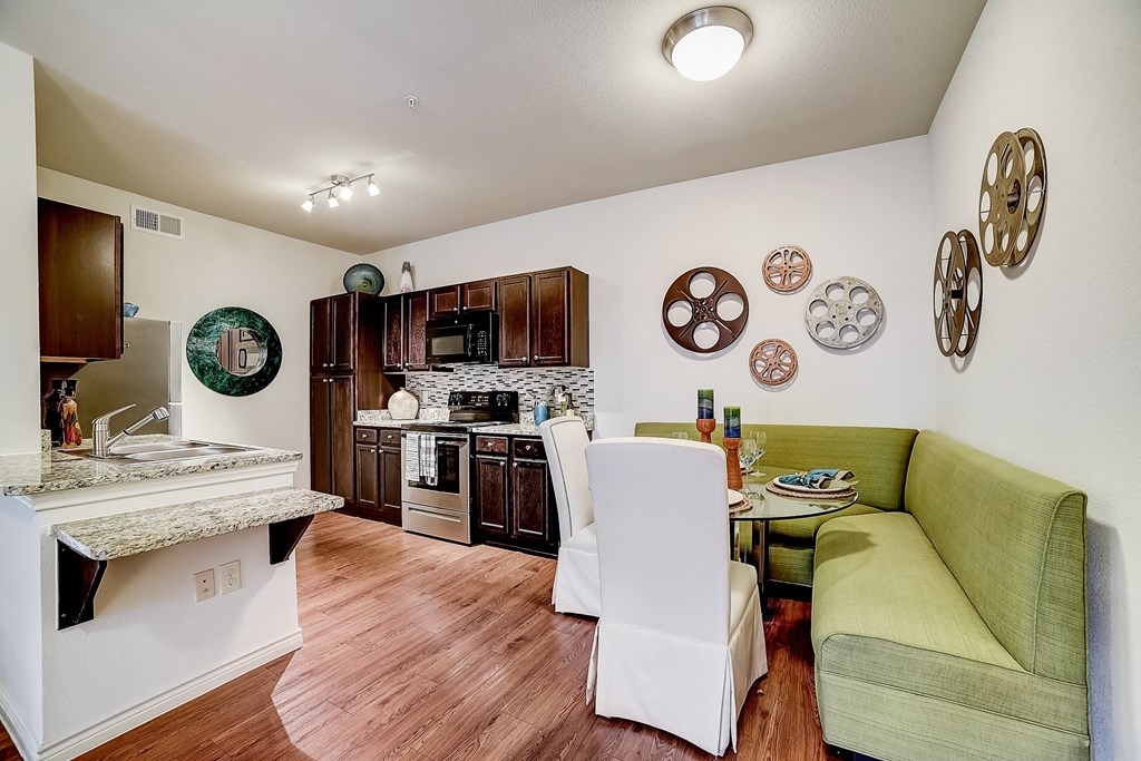 a kitchen and living room with a green couch and wood flooring