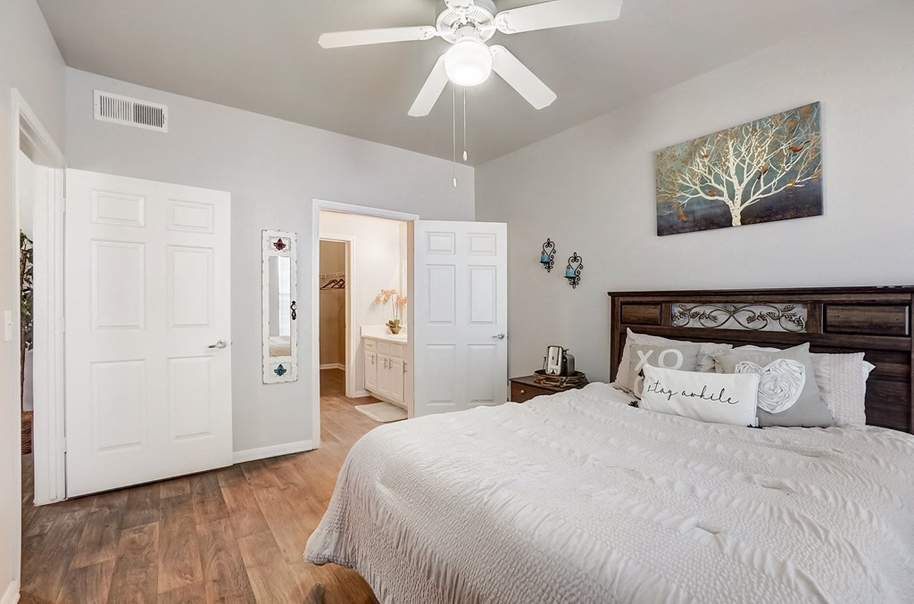 the master bedroom has a large bed and a ceiling fan