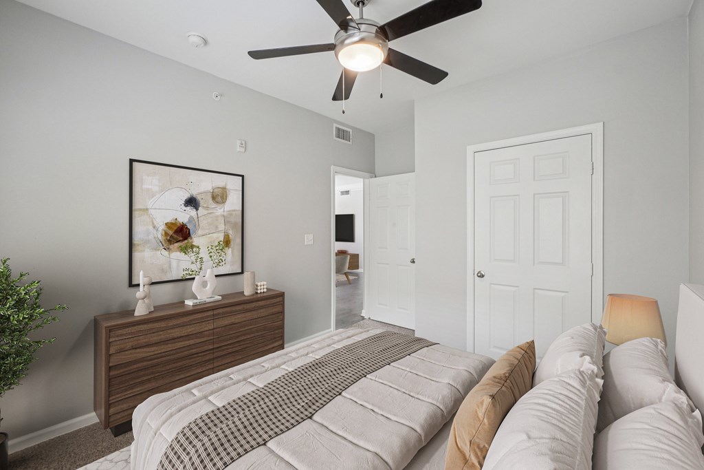A bedroom with a bed, dresser, and a ceiling fan.