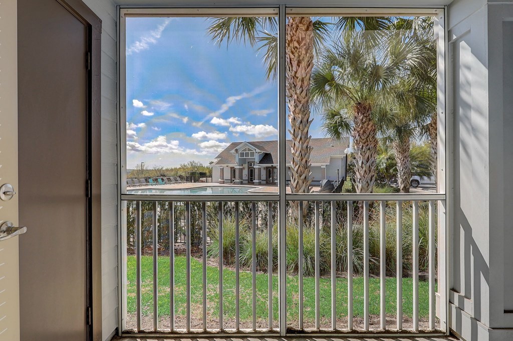 the view from the balcony of a house overlooking a pool and palm trees