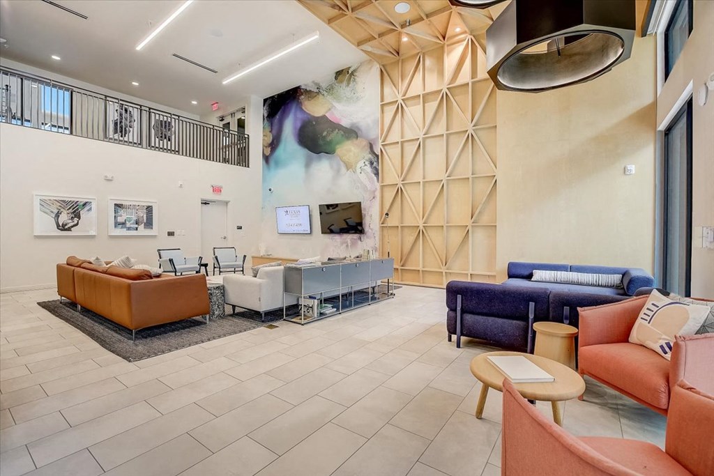 a lobby with couches and chairs and a large painting on the wall
