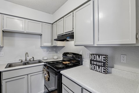 A kitchen with white cabinets and a black stove top.