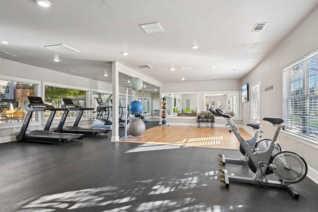 A spacious gym with a variety of equipment including a stationary bike, treadmill, and exercise ball.