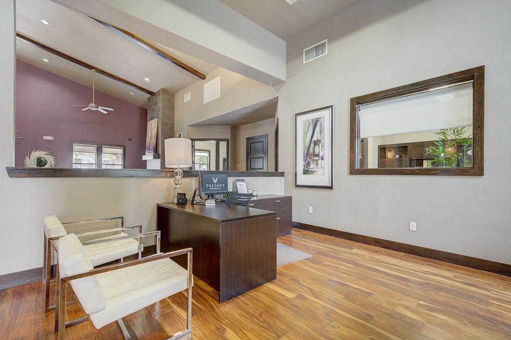a living room with a desk and chairs and a mirror
