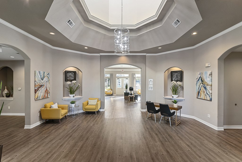 a large living room with yellow chairs and a chandelier