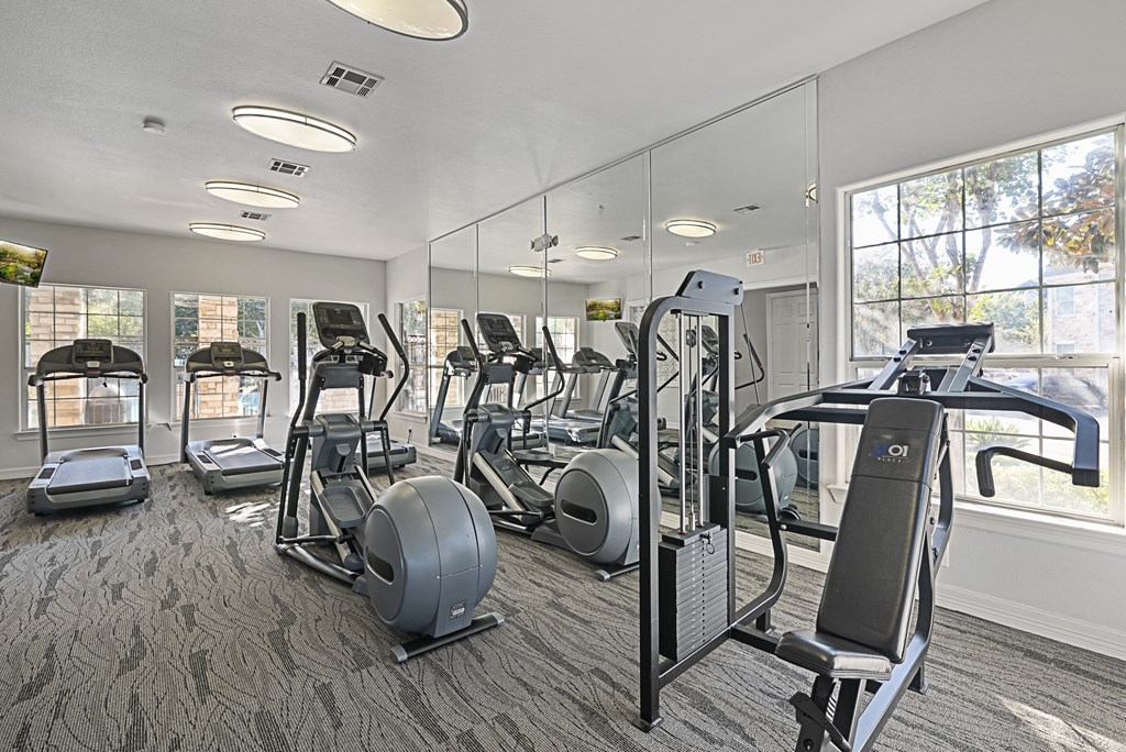 a gym with cardio equipment and mirrors in a building