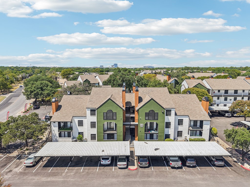 A green and white building with a parking lot in front.