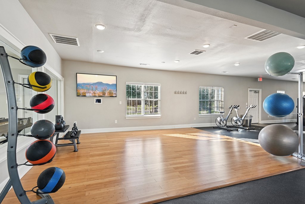 A gym with a wooden floor and a large mirror on the wall.